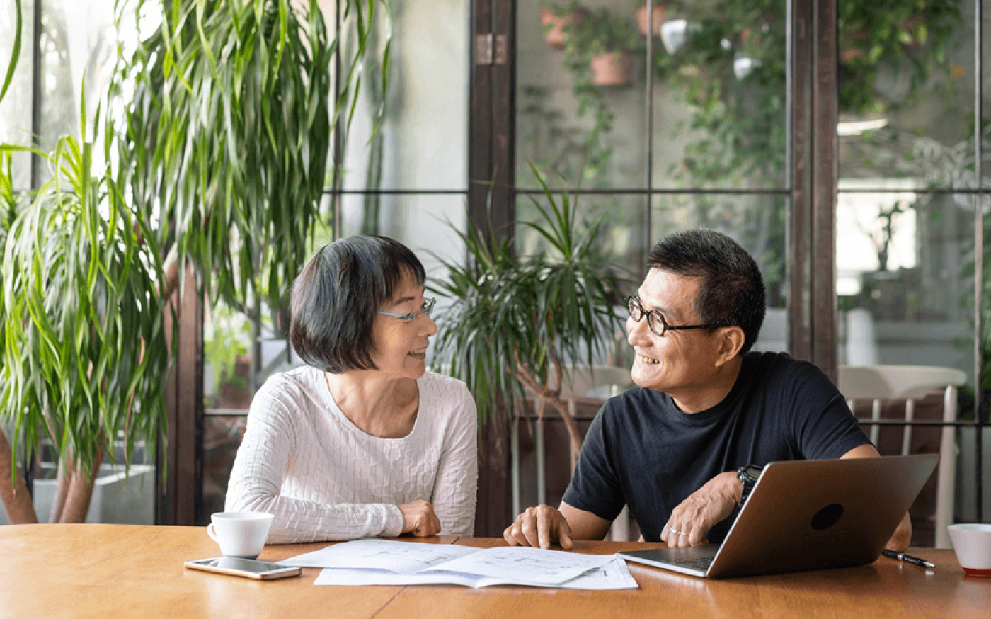 Two people sitting at a table, smiling at each other.
